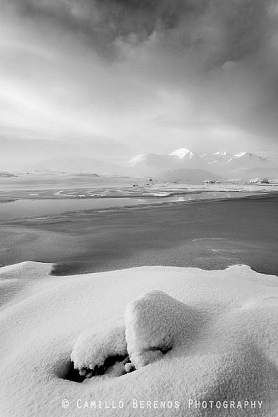 A partial reflection of the snow-covered Black Mount hills in Lochan na Stainge