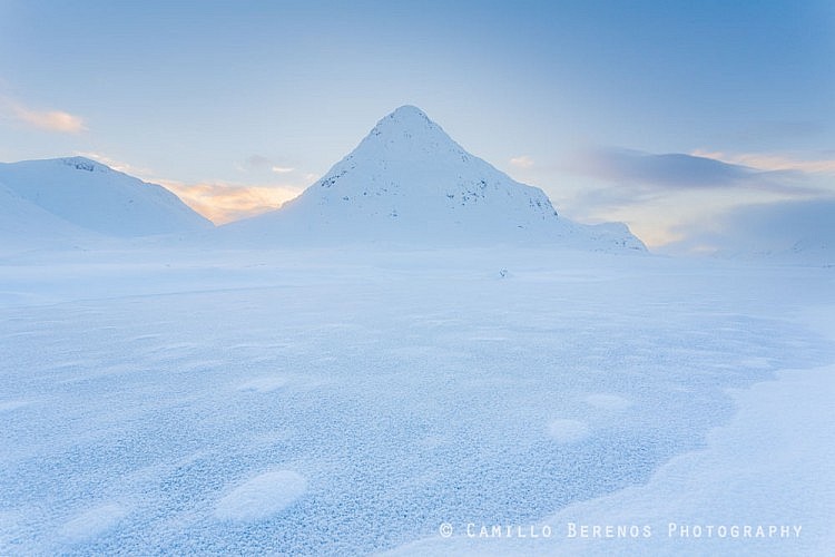 A frozen lochan with the Buachaille Etive Beag behind it during the blue hour after sunset.