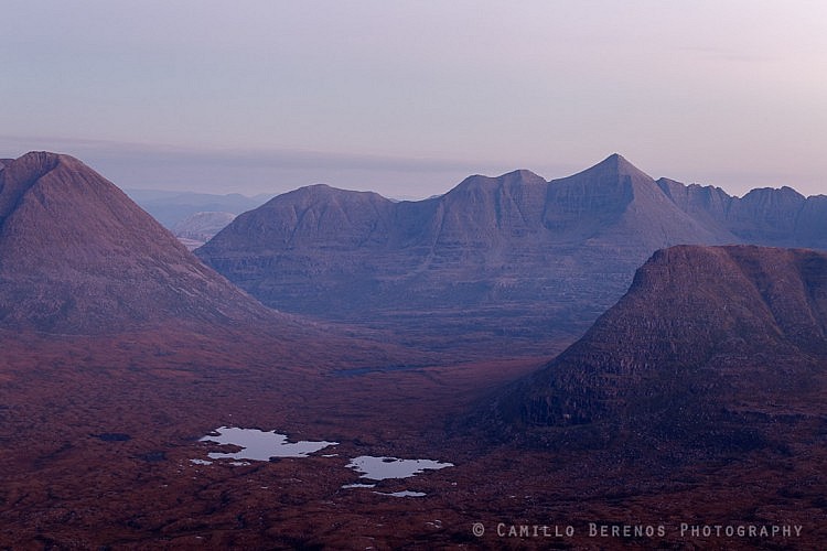 The primordial landscape of Torridon (Beinn Eighe, Liathach and Carn na Feola) unfolds below Beinn na Eoin at dusk.