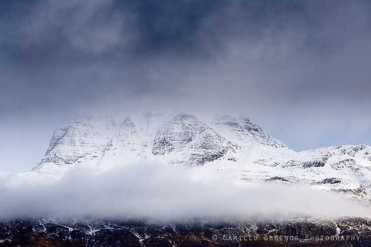 A band of low hanging clouds at the foot of a snowcapped Slioch