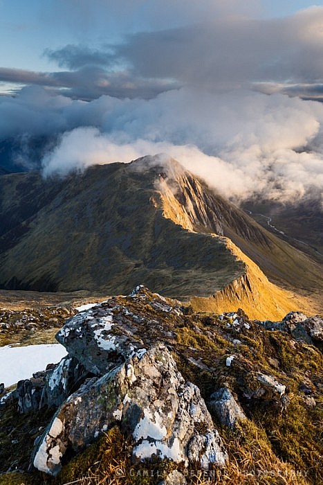 Clouds coming in over the summit of a sidelit Sgur nan Saighead at sunrise